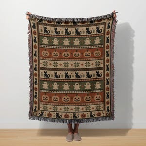 Halloween themed knit blanket with black cats, pumpkins and ghosts.