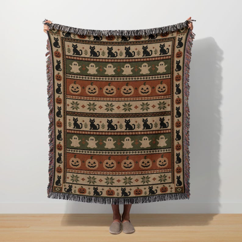 Halloween themed knit blanket with black cats, pumpkins and ghosts.