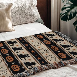 Black, tan, and orange Halloween patterned throw with cats, pumpkins, and ghosts.