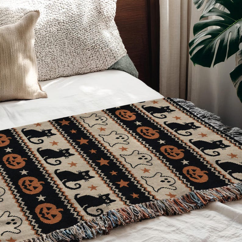 Black, tan, and orange Halloween patterned throw with cats, pumpkins, and ghosts.