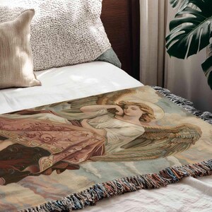 a large tapestry or blanket with an angelic figure on it, placed on a bed.