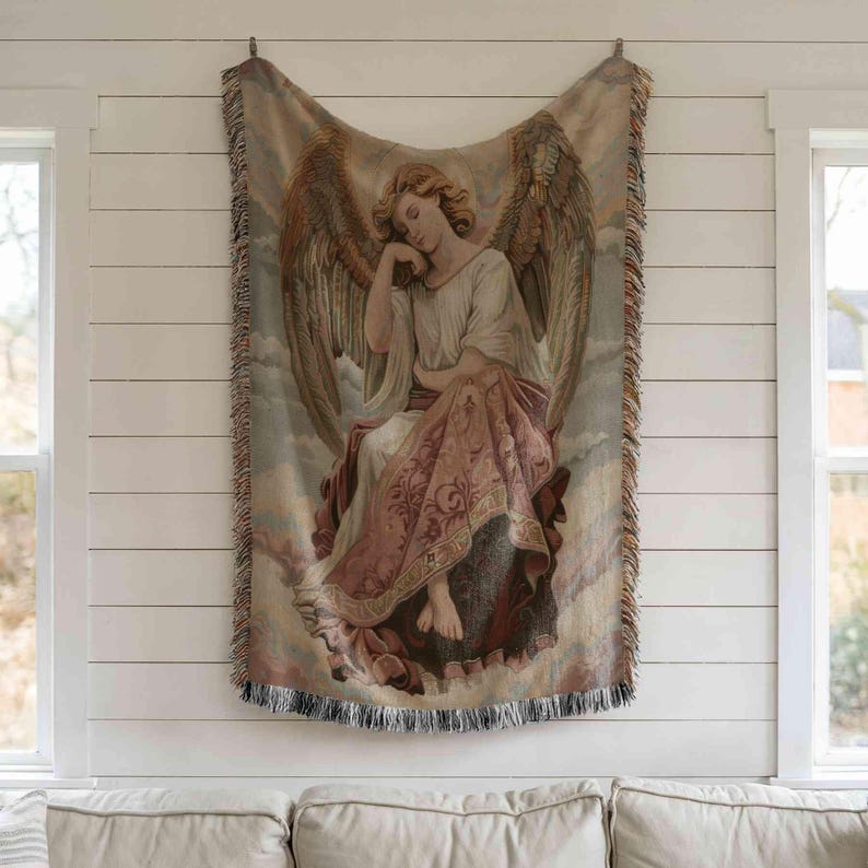 a large tapestry hanging on a white wall, depicting an angel with wings and a flowing robe.
