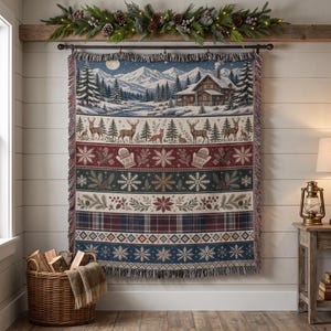 May include: A woven throw blanket featuring a winter landscape with a log cabin, snow-covered mountains, and pine trees. The design includes horizontal bands of deer, foxes, mittens, snowflakes, pine branches, and plaid patterns with fringed edges.