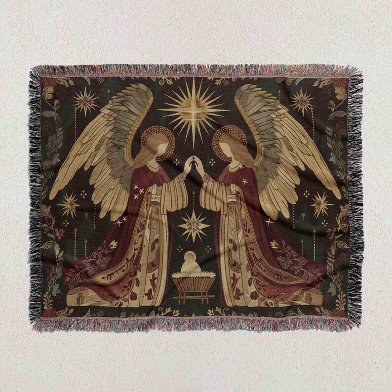 The image is a tapestry or blanket featuring two angels with wings, one on each side, standing in front of a baby Jesus. The angels are depicted in a decorative and ornate style, with intricate patterns and designs. The background of the tapestry is dark, with stars and a sun shining brightly, creating a festive and celebratory atmosphere.