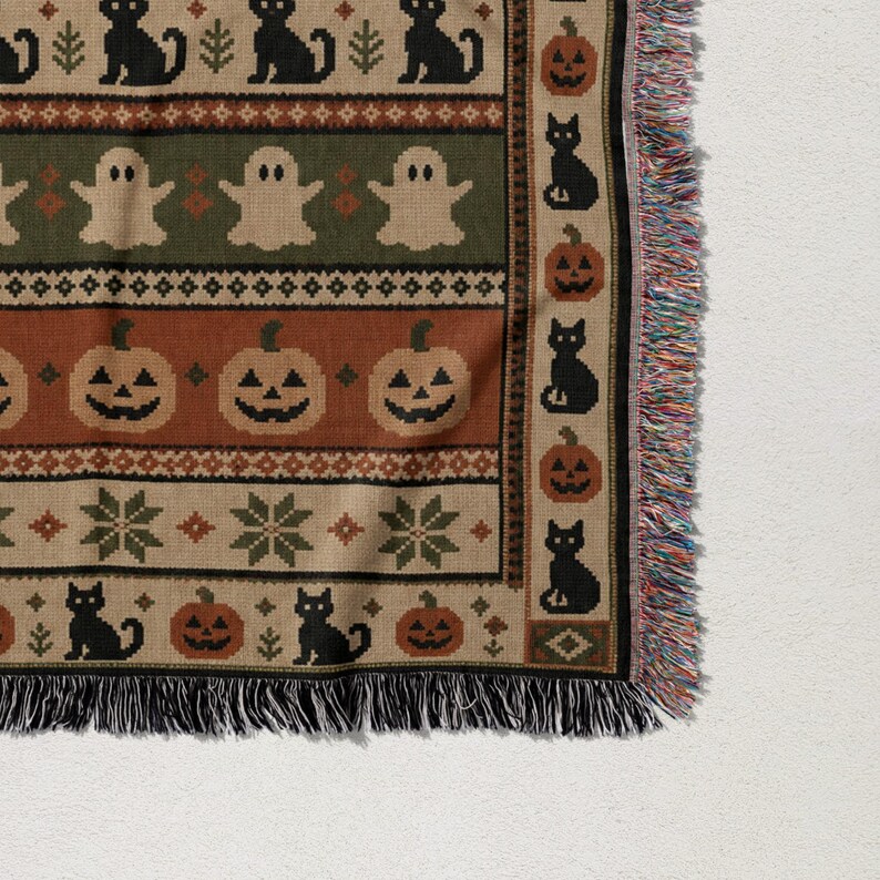 Woven blanket with black cats, ghosts, pumpkins, and snowflake patterns.