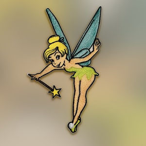 May include: Embroidered patch featuring a cartoon fairy with blonde hair, green dress, and teal wings. The fairy is holding a wand with a star-shaped tip. The patch has a tan background and is suitable for clothing or accessories.