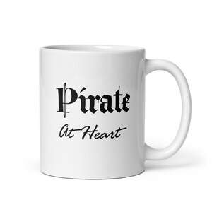 May include: White ceramic mug with black text that reads "Pirate At Heart".