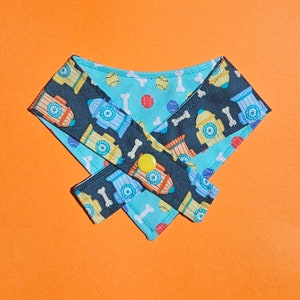 May include: A blue and black dog bandana with a fire hydrant and bone pattern. The bandana is tied in a knot and has a yellow button.