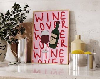 Könnte beinhalten: Ein gerahmter rosa Druck mit den roten Worten "WINE LOVER". Der Druck zeigt ein Weinglas und eine grüne Weinflasche mit einem Korkenzieher. Der Druck wird auf einer weißen Arbeitsplatte angezeigt.