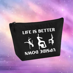 Può includere: Pochette per cosmetici nera con cerniera, con la scritta bianca "LIFE IS BETTER UPSIDE DOWN". Presenta sagome bianche di ballerine di pole dance. Lo sfondo è un mix di viola, rosa e blu.
