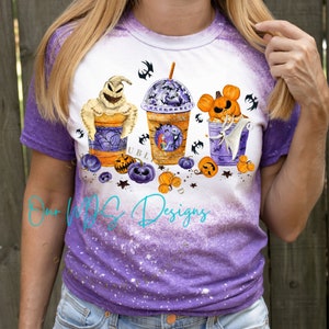 K&ouml;nnte beinhalten: Ein wei&szlig;es T-Shirt mit einem lilafarbenen Ombre-Design, das ein Halloween-Motiv zum Thema Nightmare Before Christmas zeigt. Das Design enth&auml;lt drei Becher mit den Charakteren Jack Skellington, Sally und Oogie Boogie. Die Becher sind mit Halloween-Getr&auml;nken gef&uuml;llt und von K&uuml;rbissen und Flederm&auml;usen umgeben.