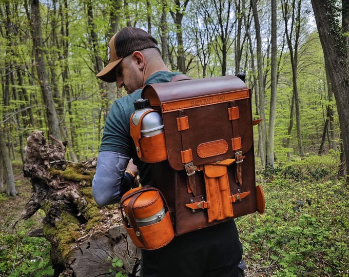 Handmade  leather bushcraft bag  a bushcraft axe,  handmade folding pan, aluminum water carrier,  camping pot, bushcraft drill, and bowsaw
