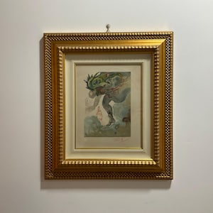May include: A framed watercolour painting of a mythical creature with green and blue hues. The creature is depicted in a dynamic pose, with its wings spread out. The painting is set against a white background and is framed in a gold-coloured frame.