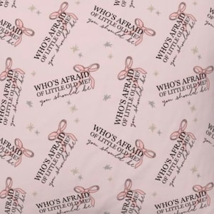 May include: A pink background with a repeating pattern of a pink bow and the text "Who's Afraid of Little Old Me? You should be."
