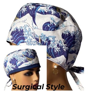 May include: A surgical style scrub cap with a blue and white wave pattern. The cap has a navy blue trim and ties at the back. The cap is shown on a model wearing earrings.
