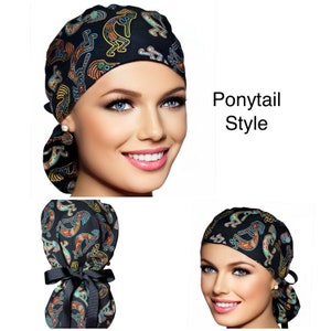May include: Black ponytail style scrub cap with a colorful Kokopelli design. The cap features a black ribbon tie and is made of a soft, comfortable material. The text "Ponytail Style" is visible.