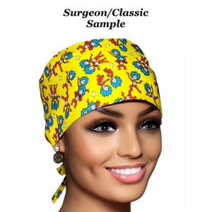 May include: Yellow surgical scrub hat with a colorful print of cartoon characters. The hat has a tie at the back.