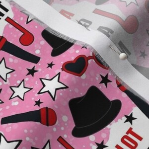 May include: Pink fabric with a repeating pattern of black and red stars, microphones, hats, and heart-shaped sunglasses. The text "Talent" and "Spotlight" are visible in the pattern.
