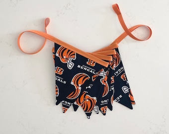 May include: A black and orange fabric bunting with the words "Cincinnati Bengals" and the team logo. The bunting is made of multiple triangular flags connected by orange ribbon.