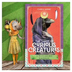May include: A tarot deck featuring a purple-robed crow with a crescent moon and feathers. The title "The Tarot of Curious Creatures" is printed in bold, white letters. The text "A 78 (+1) card deck & guidebook" is printed in green on a white ribbon.