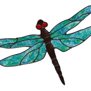 K&ouml;nnte beinhalten: Eine Libelle aus Glasmalerei mit blauen und gr&uuml;nen Fl&uuml;geln und einem schwarzen K&ouml;rper. Die Libelle hat rote Augen.