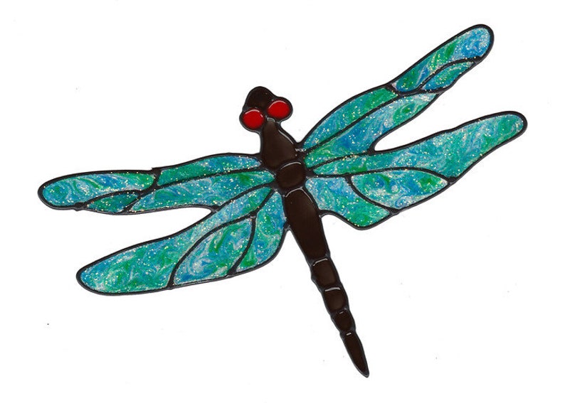 K&ouml;nnte beinhalten: Eine Libelle aus Glasmalerei mit blauen und gr&uuml;nen Fl&uuml;geln und einem schwarzen K&ouml;rper. Die Libelle hat rote Augen.
