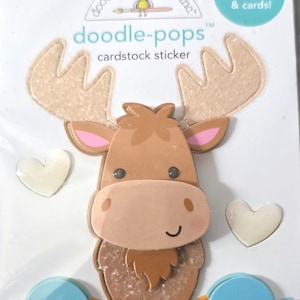 May include: Cardstock stickers featuring a moose, two blue birds, and two white hearts. The moose is brown with tan antlers and pink ears. The birds have orange beaks and feet. The stickers are perfect for scrapbooks and cards.