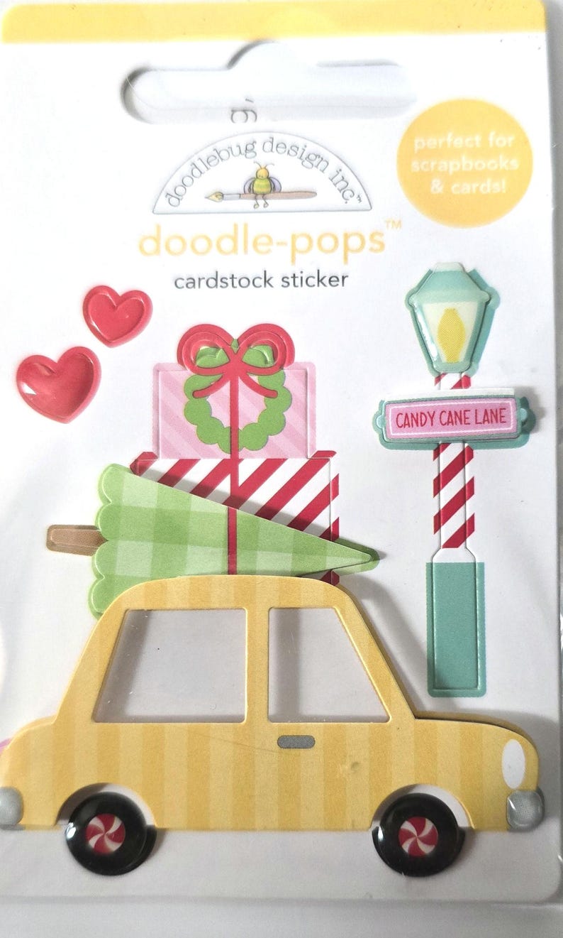 May include: Cardstock stickers featuring a yellow car, Christmas presents, a Christmas tree, and a street sign that reads "Candy Cane Lane." The stickers also include red hearts. The brand name is "doodle-pops".
