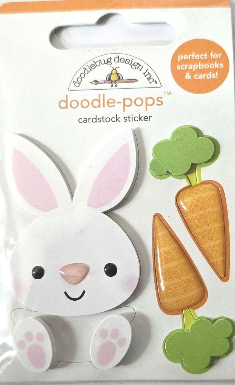 May include: Doodlebug Design Inc. "doodle-pops" cardstock sticker set featuring a white bunny with pink ears and paws, and two orange carrots with green tops. The sticker set is designed for scrapbooks and cards.