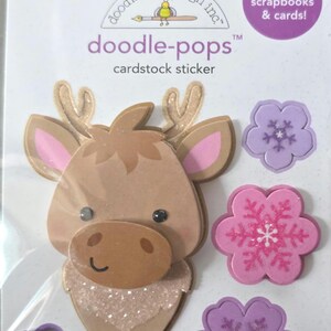 May include: Doodlebug Design Inc. cardstock sticker set featuring a reindeer and flower designs. The reindeer has brown fur, pink ears, and glitter accents. The flowers are pink and purple with snowflake details. Perfect for scrapbooks and cards.