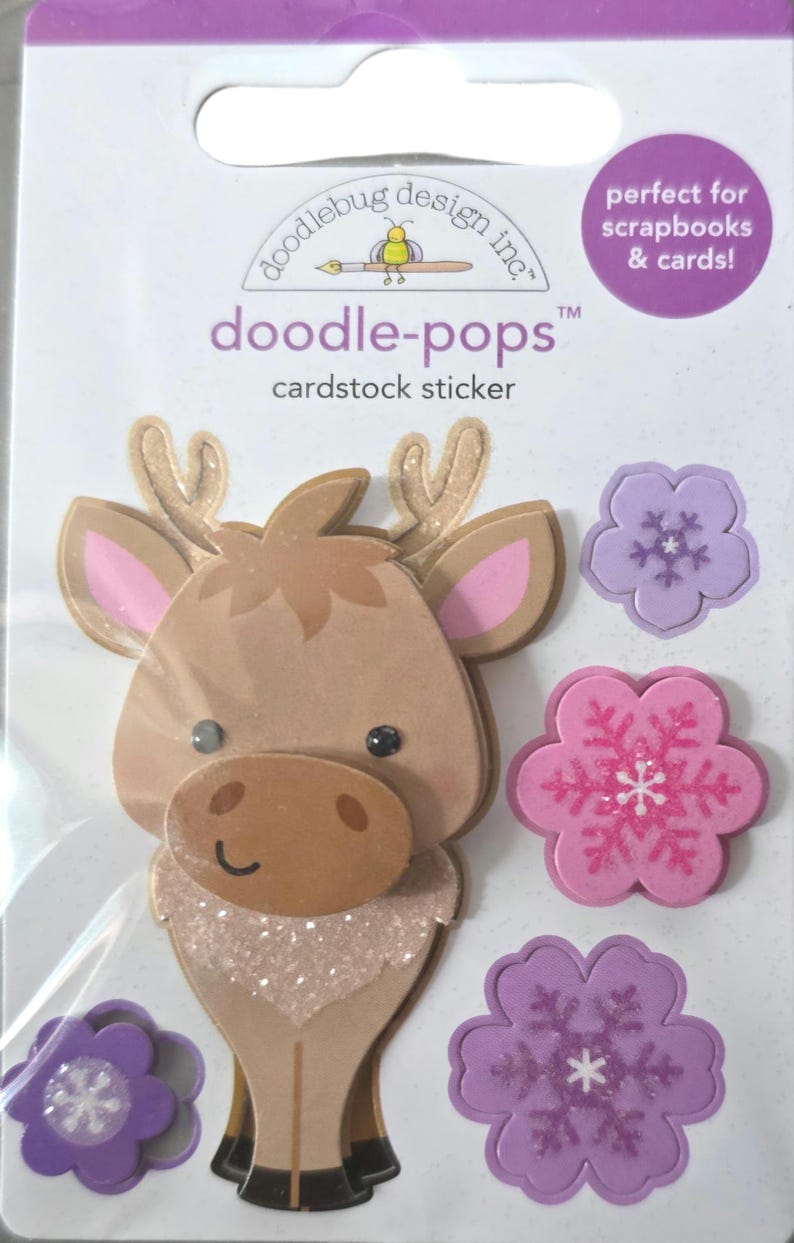 May include: Doodlebug Design Inc. cardstock sticker set featuring a reindeer and flower designs. The reindeer has brown fur, pink ears, and glitter accents. The flowers are pink and purple with snowflake details. Perfect for scrapbooks and cards.
