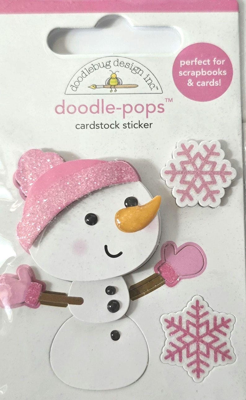 May include: Cardstock sticker set featuring a snowman with a pink hat, mittens, and a carrot nose, along with two pink and white snowflakes. The sticker set is labeled "doodle-pops" and is designed for scrapbooks and cards.