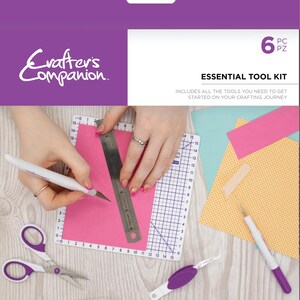 Könnte beinhalten: Ein Crafter's Companion Essential Tool Kit in Lila und Weiß. Das Set enthält ein Bastelmesser, ein Stechwerkzeug, eine Pinzette, eine 11,4 cm Präzisionsschere, ein 15 cm Metalllineal und eine 15 cm selbstheilende Schneidematte.
