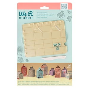 May include: A We R Makers carton stamp board kit. The kit includes a beige grid board, a white scoring tool, and various stamps. The packaging features a variety of colorful carton village designs. Text on the packaging reads "Score, stamp & assemble festive villages, spooky haunts, & playful cartons in a snap!"