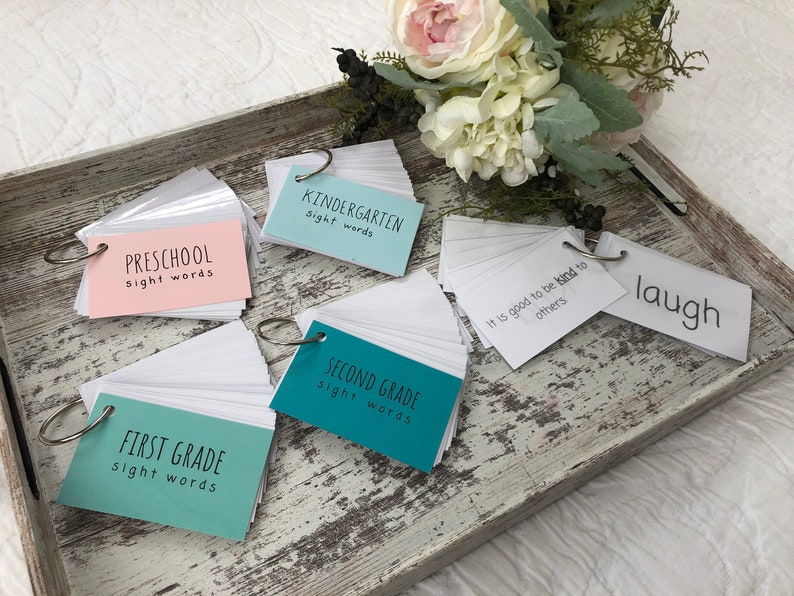 May include: A set of five ring-bound flashcard sets for different grade levels. The cards are labelled "Preschool sight words", "Kindergarten sight words", "First Grade sight words", "Second Grade sight words", and "It is good to be kind to others". There is also a single flashcard with the word "laugh" on it.