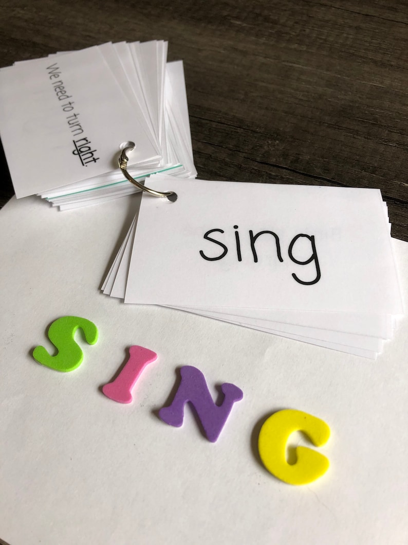 May include: A set of white flashcards with the word "sing" written on them. The word "sing" is spelled out with colourful foam letters.