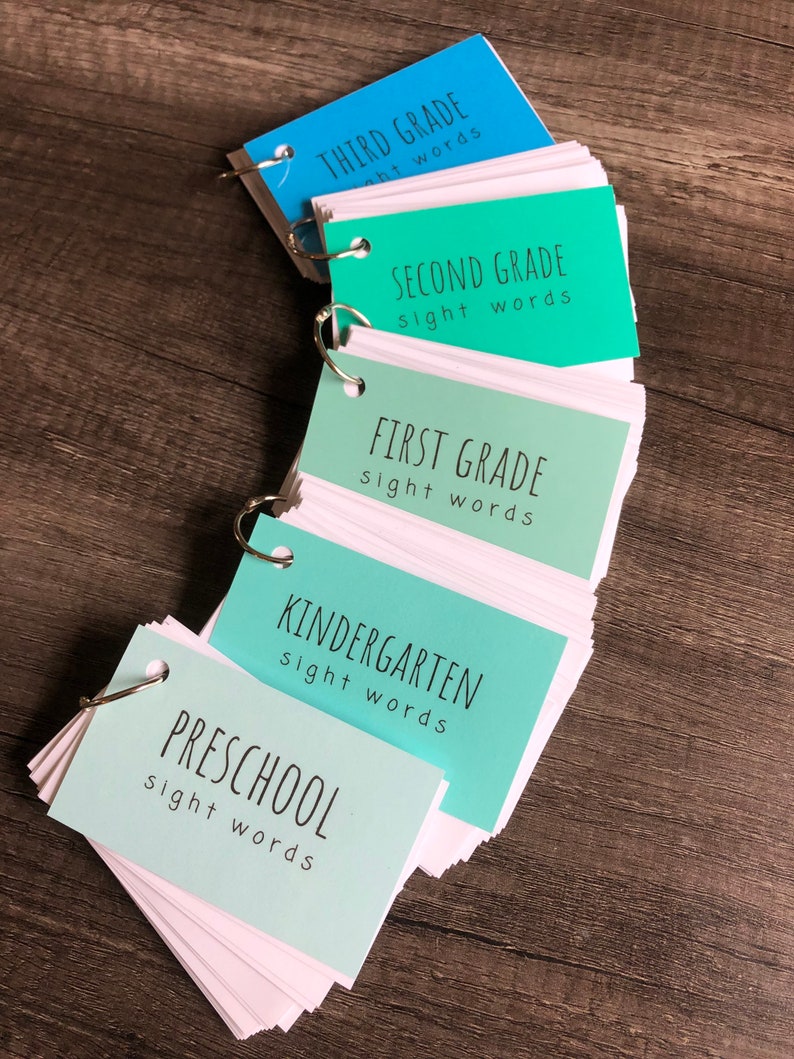 May include: A set of five colourful flashcard sets for different grade levels, starting with preschool and ending with third grade. Each set has a different colour and includes the words "sight words" on the front.
