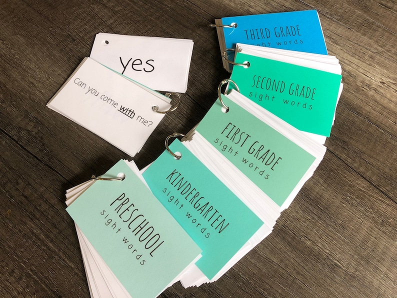 May include: A set of flash cards for teaching sight words, organized by grade level. The cards are color-coded, with green for kindergarten through first grade and blue for second and third grade. The cards are labeled with the grade level and the words "sight words".