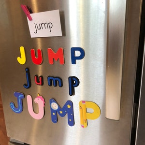 May include: A refrigerator with a white note that says "jump" and colourful magnetic letters spelling out "jump" in different styles. The letters are in blue, yellow, red, pink, and black.