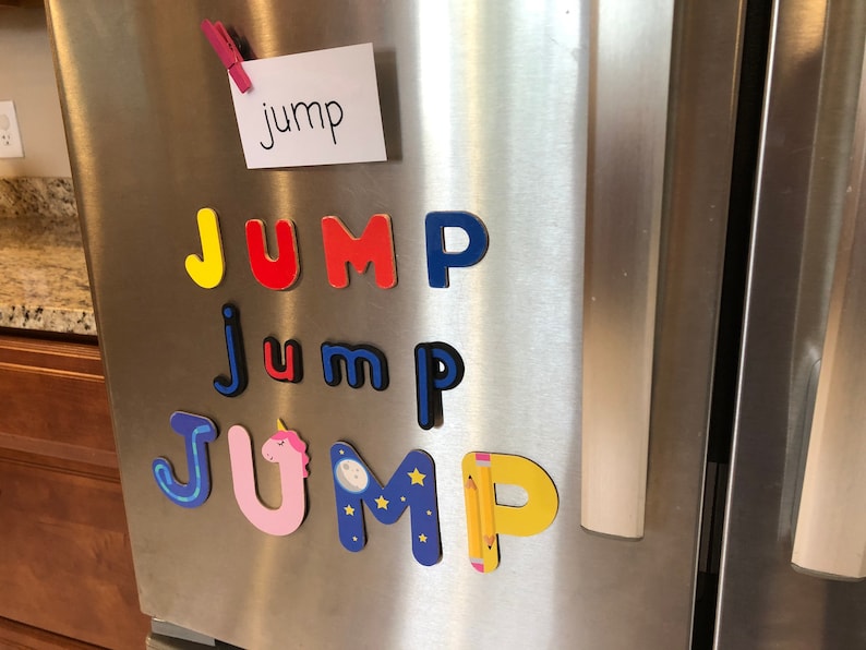 May include: A refrigerator with a white note that says "jump" and colourful magnetic letters spelling out "jump" in different styles. The letters are in blue, yellow, red, pink, and black.