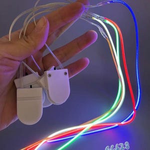 May include: Three white plastic battery-operated controllers connected to thin, flexible light-up cords that glow in vibrant orange, green, and blue. The cords are illuminated, and the text GC628 is visible in the lower right corner of the image.