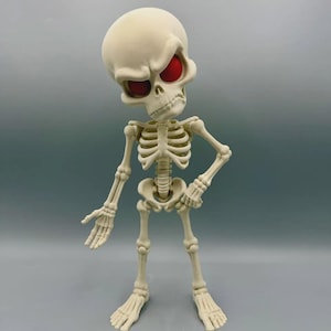 May include: A stylized off-white skeleton figurine with an oversized head and expressive, deep-set red eyes. The figure features a cartoonish skeletal structure with a prominent brow, a hand extended outward, and the other hand resting on its hip.