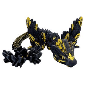 May include: A black and yellow 3D printed dragon figurine with intricate details. The dragon has a curled tail and a fierce expression.