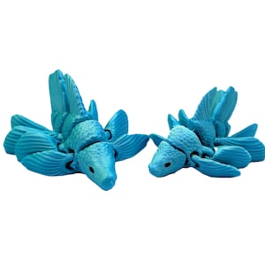 Peut inclure: Deux figurines articulées de créatures marines turquoise. Chaque figurine a un corps segmenté, de grandes nageoires et une tête détaillée avec de petits yeux sombres. Les figurines sont posées sur un fond blanc.
