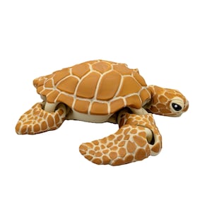 Könnte beinhalten: Detaillierte, hellbraune Meeresschildkrötenfigur mit strukturierter Schale und Flossen. Der Panzer der Schildkröte weist ein geometrisches Muster auf, und ihre Augen sind sichtbar. Die Figur ist so gestaltet, dass sie einer echten Meeresschildkröte ähnelt.