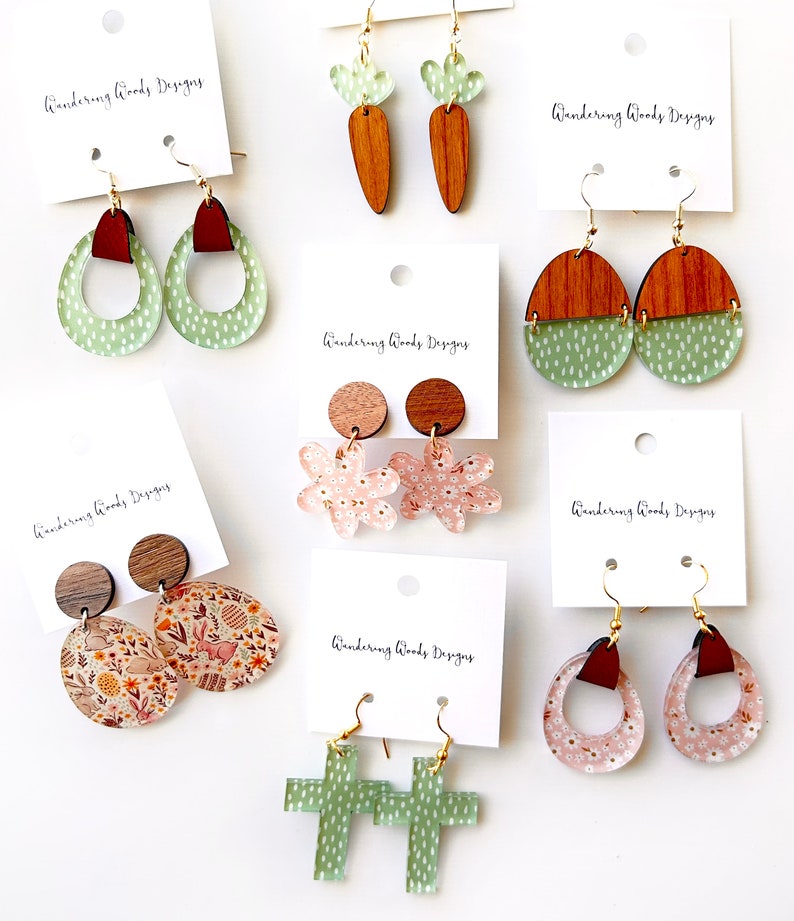 May include: Assortment of handmade acrylic earrings with various designs, including floral, bunny, carrot, cross, and geometric shapes. The earrings are all in shades of green, pink, and brown.