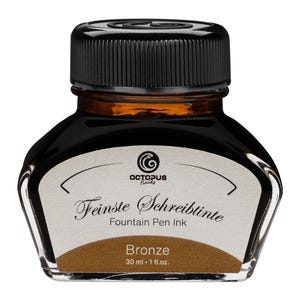 May include: A glass bottle of Octopus Fluids fountain pen ink in Bronze. The bottle has a black cap and a white label with the text "Feinste Schreibtinete Fountain Pen Ink". The bottle contains 30 ml or 1 fl. oz. of ink.