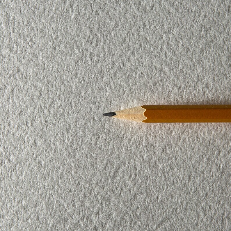 May include: A yellow pencil with a black eraser on a white textured surface.