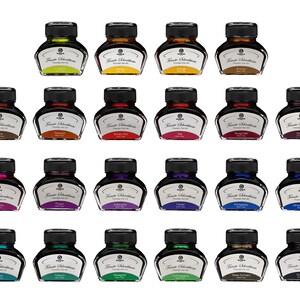 May include: A collection of twenty-one bottles of fountain pen ink in various colors. Each bottle has a black cap and a label with the brand name. The ink colors include green, yellow, brown, red, purple, blue, and teal.