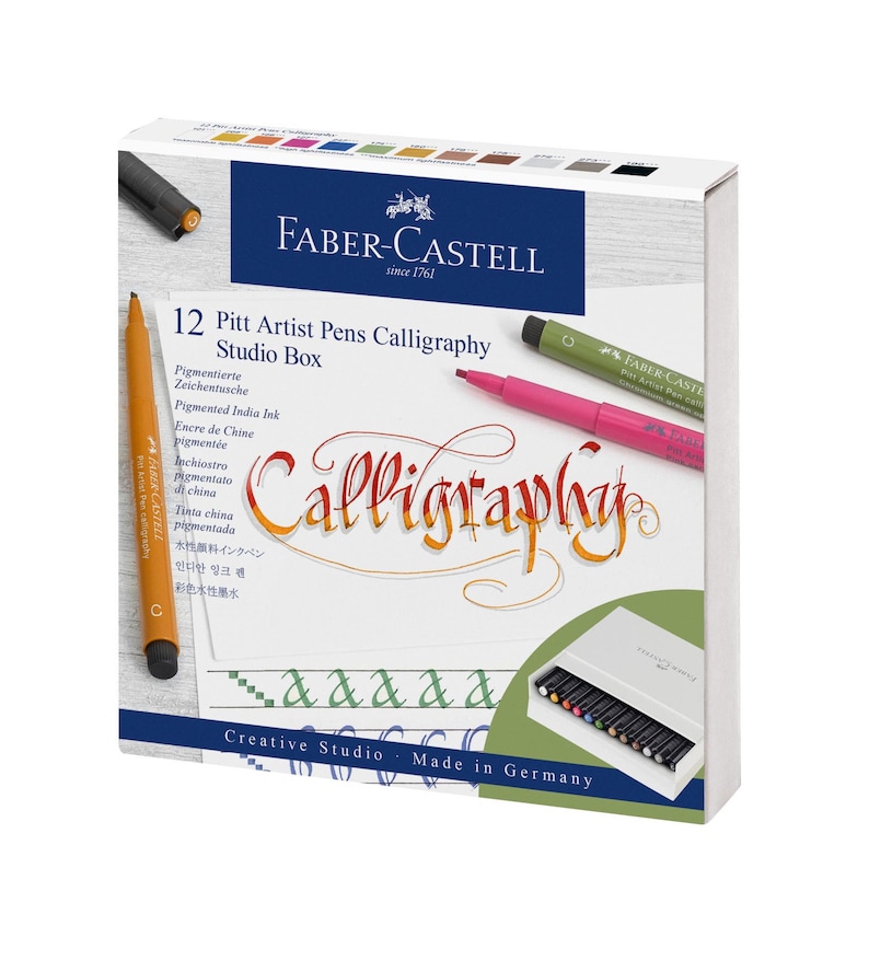 Pu&ograve; includere: Una scatola di 12 Faber-Castell Pitt Artist Pens Calligraphy Studio Box. La scatola &egrave; bianca con un bordo verde e bianco. La scatola contiene un'immagine di una penna e il testo "Calligraphy" in un carattere decorativo. La scatola contiene anche il testo "Creative Studio - Made in Germany".